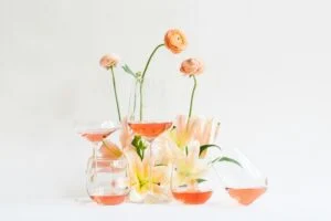 glasses of rosé wine among a small display of spring flowers on a white backdrop