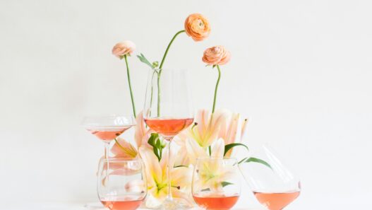 glasses of rosé wine among a small display of spring flowers on a white backdrop