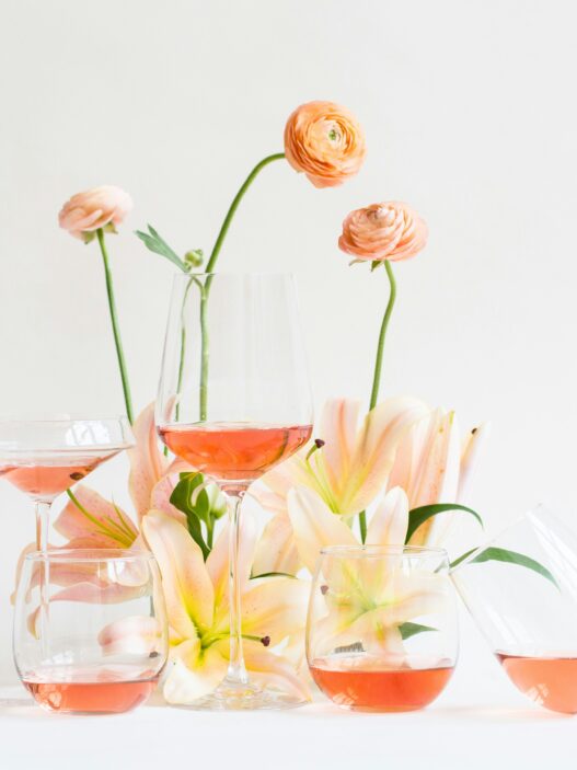 glasses of rosé wine among a small display of spring flowers on a white backdrop