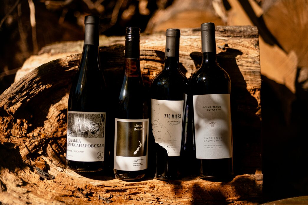 Four bottles of wine perched against a wood log