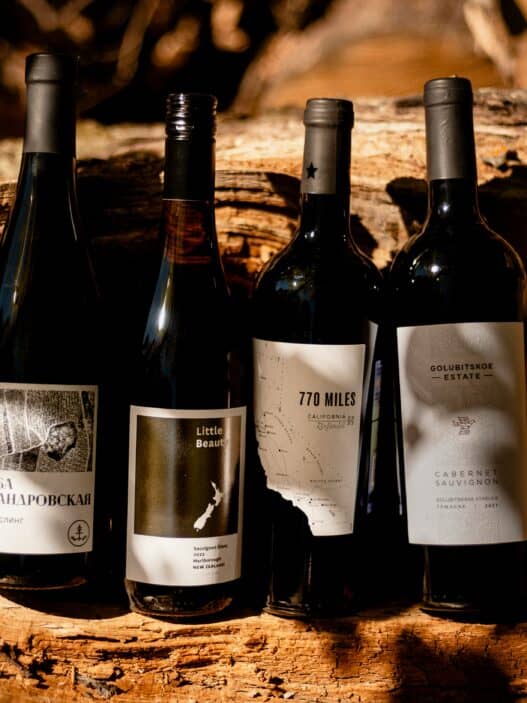 Four bottles of wine perched against a wood log